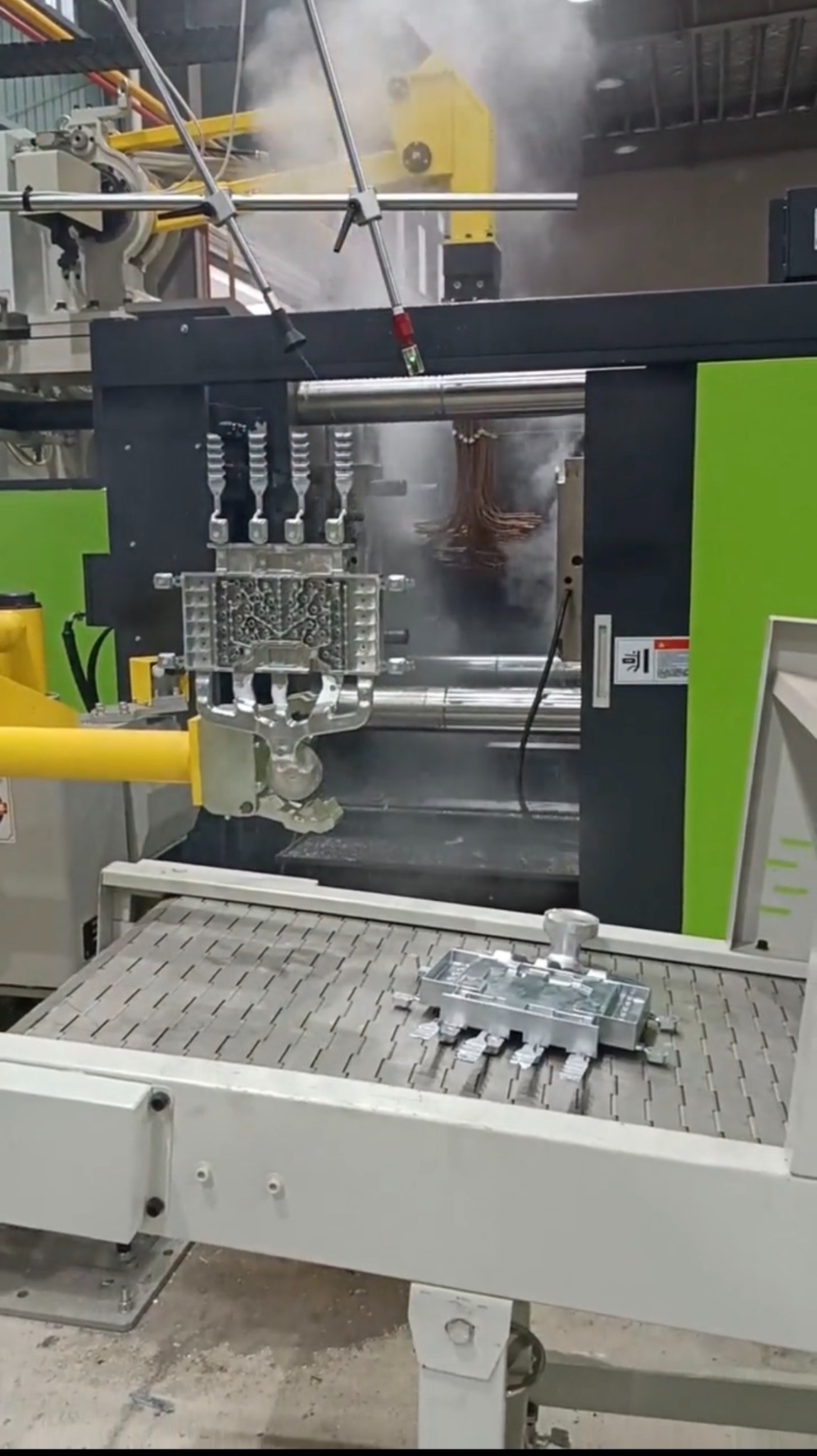 Die casting production reference showing an opened mold area on a die casting machine with a casting and runner system visible after the shot.