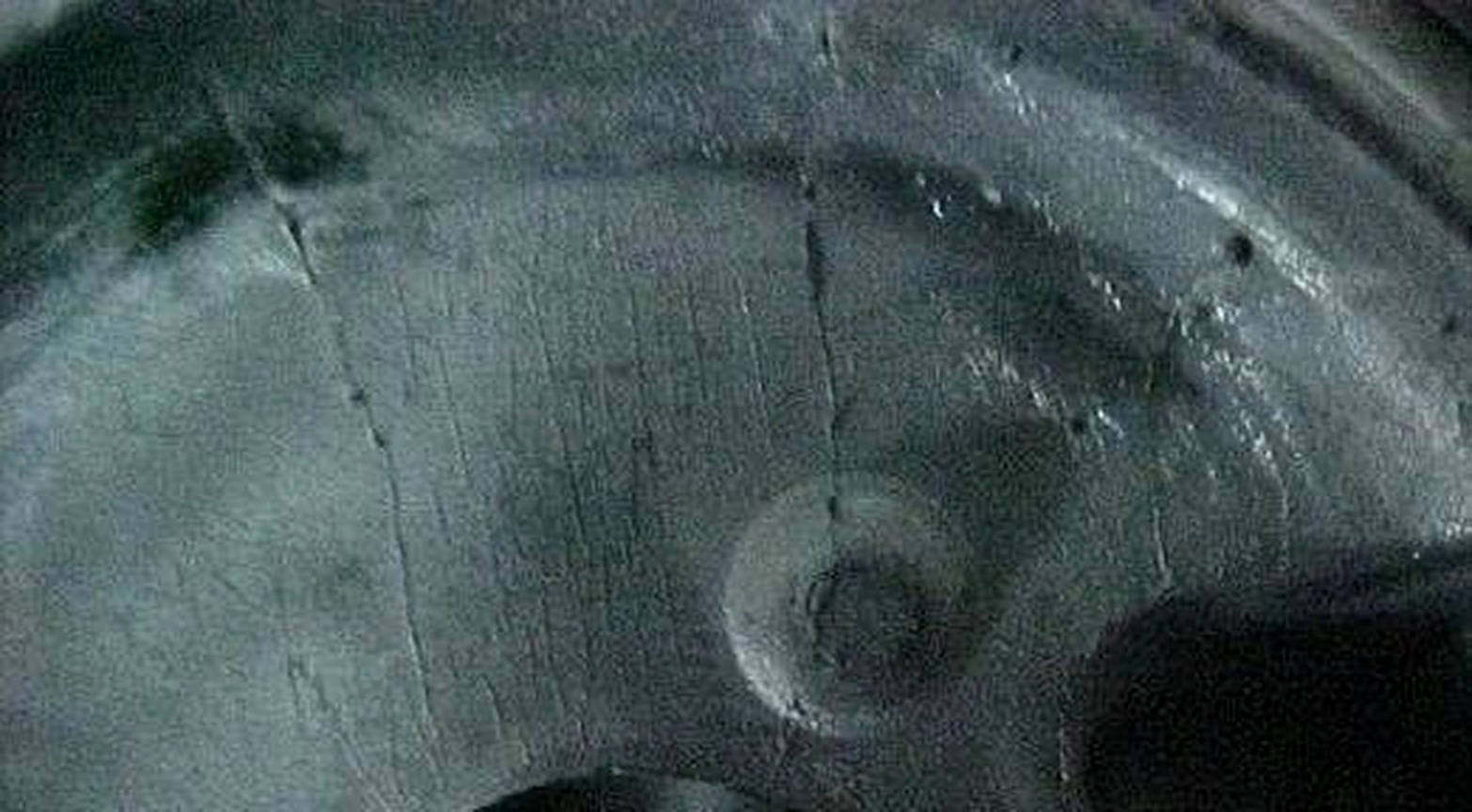 Close-up of an HSX aluminum die casting showing fine net-like heat-check marks on the cast surface.