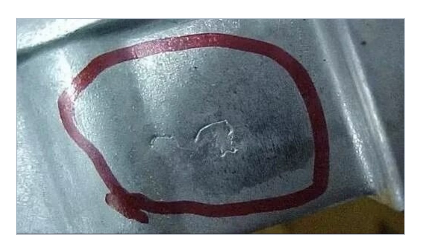 Close-up example of an aluminum die casting with an irregular recessed linear cold shut defect highlighted by a red outline.