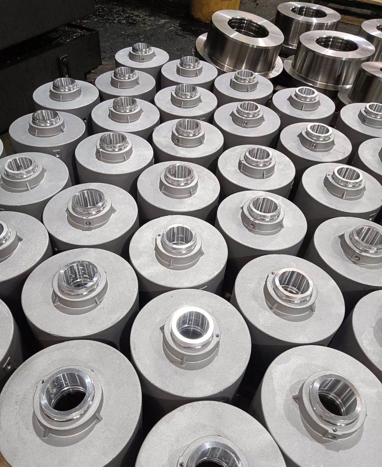 Multiple cylindrical aluminum housings with machined bores arranged in a production area
