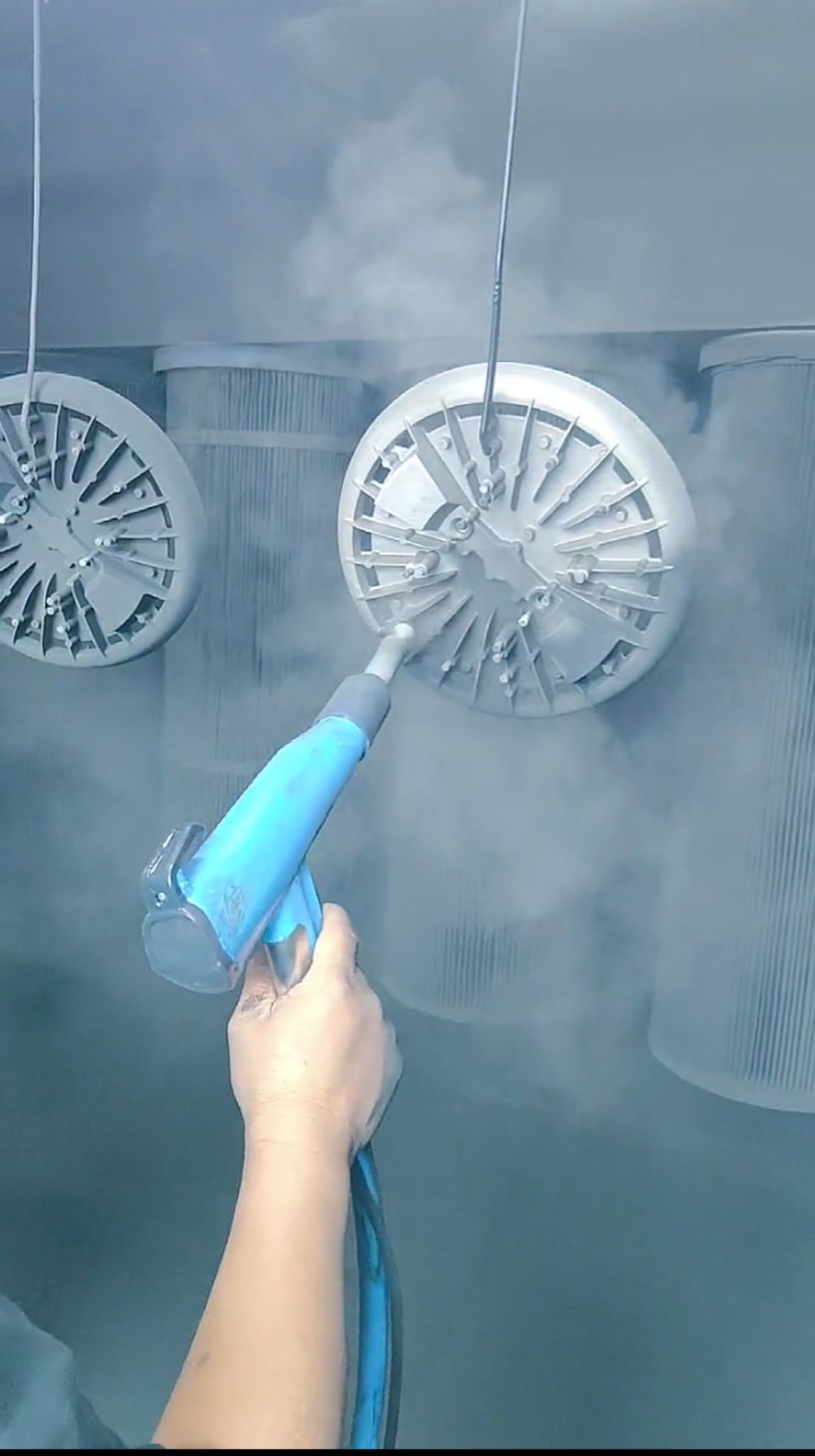 Electrostatic powder coating of aluminum die cast parts in a spray booth before thermal curing.