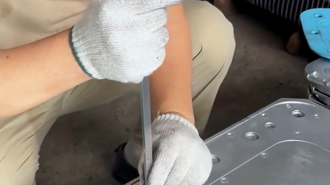 HSX worker using a vernier caliper to perform an in-process dimensional check on a batch of aluminum die cast parts.