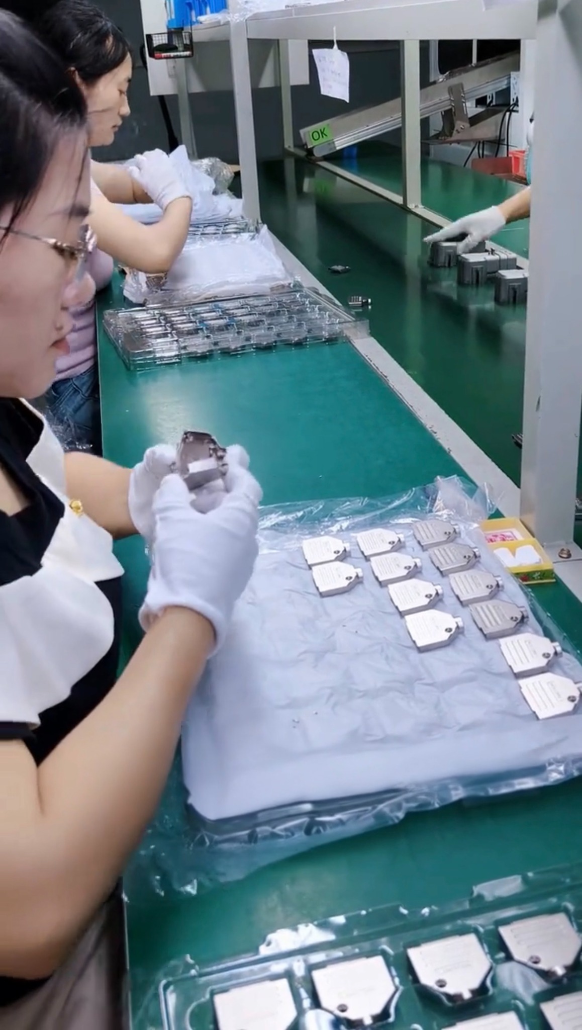 Workers visually examining small metal components and arranging them at a workbench.