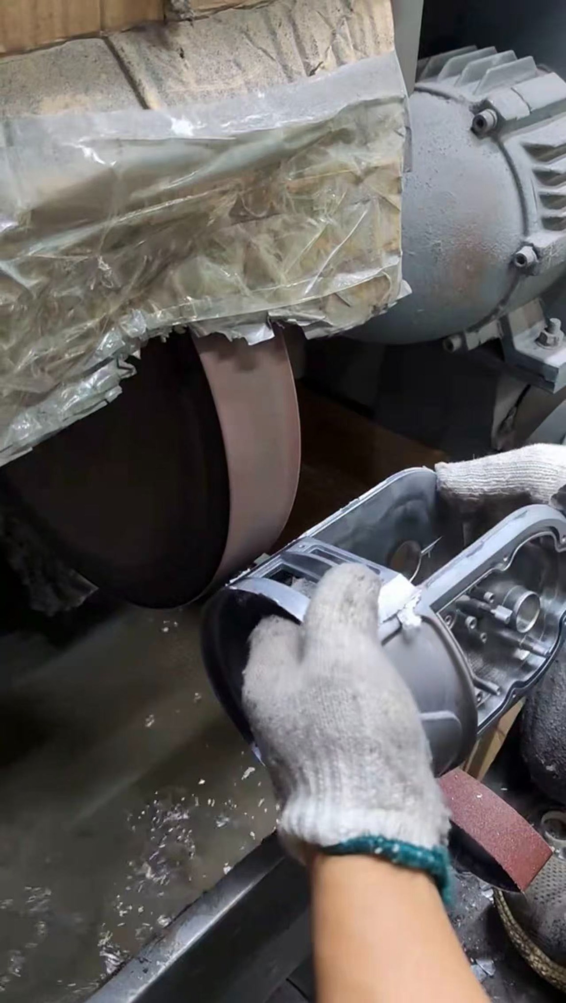 Operator polishing a custom aluminum casting at a wheel.